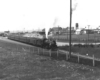 Steam locomotive with passenger train at station.