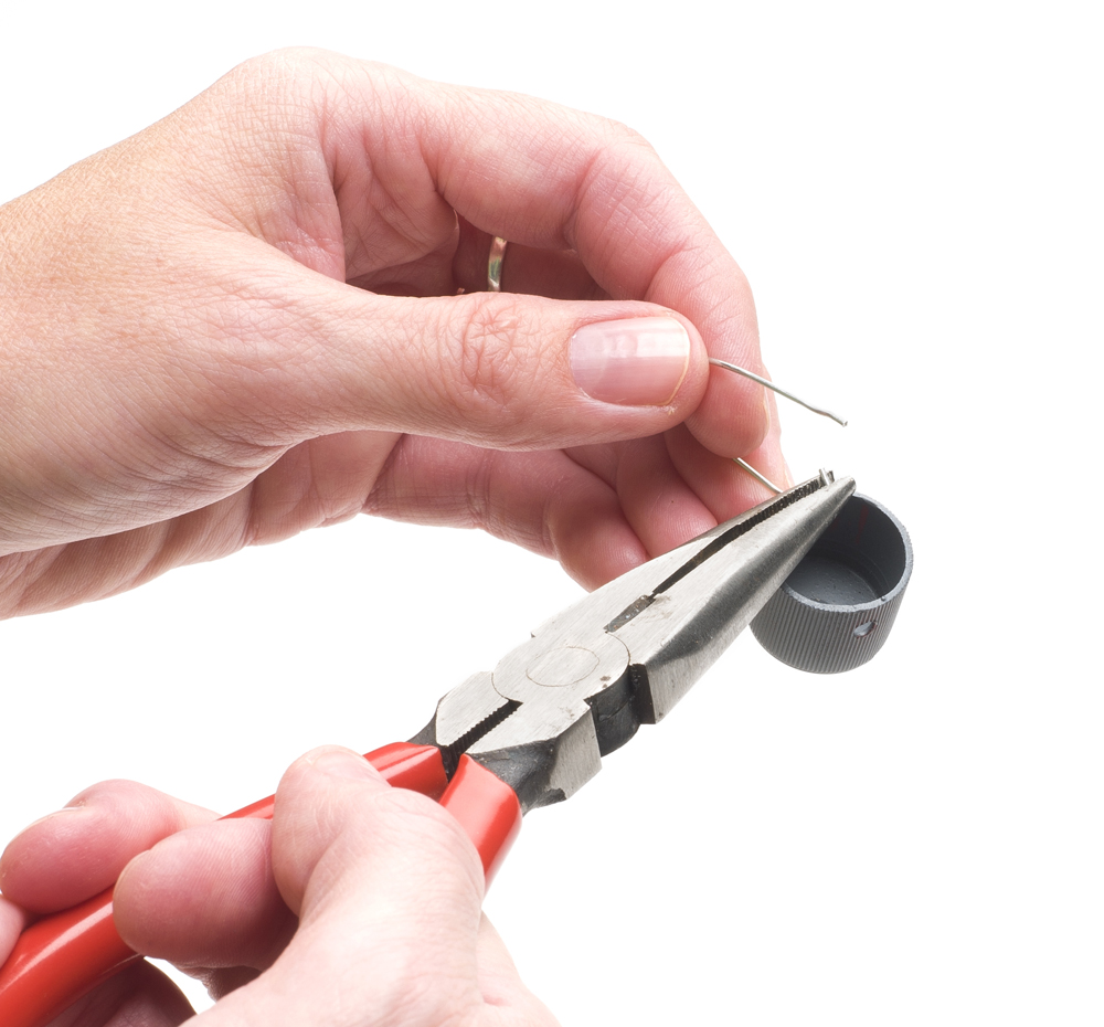 Needlenose pliers bend wire to form a basket from a small cap.