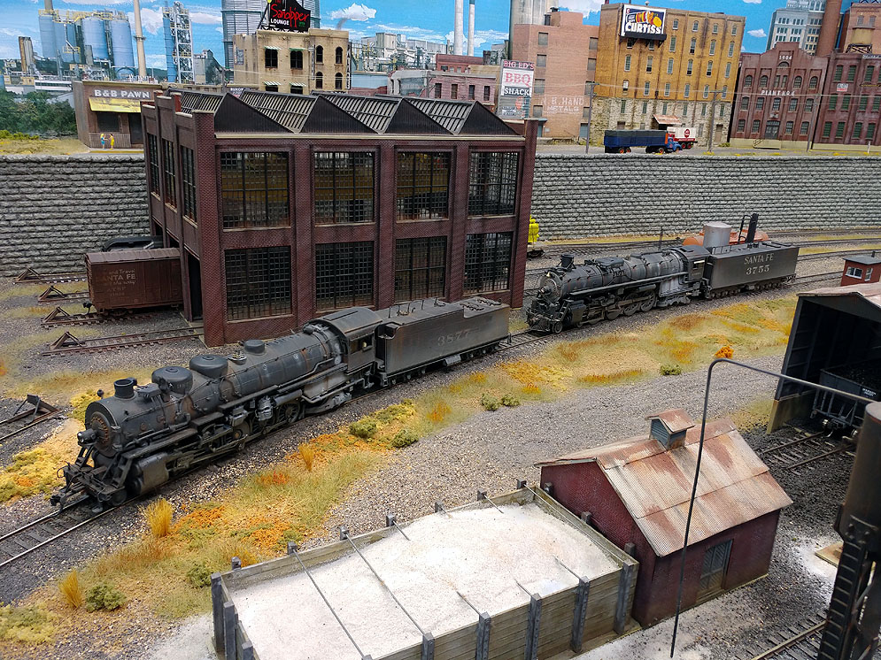 High-angle view of Santa Fe 2-10-2 and 4-8-4 facing left with sand house in foreground and brick car shup in background