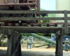 Two workers with shovels are framed by the legs of an unloading trestle bearing a gravel hopper