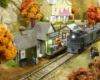 A green “Doodlebug” motorcar pulls up to the platform at a small, yellow, wood-frame depot