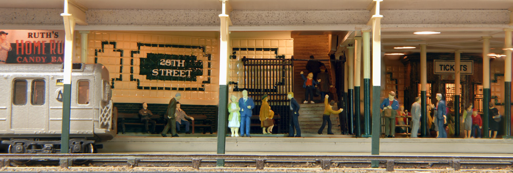 Passengers stand about on a subway platform as a subway train enters to the left