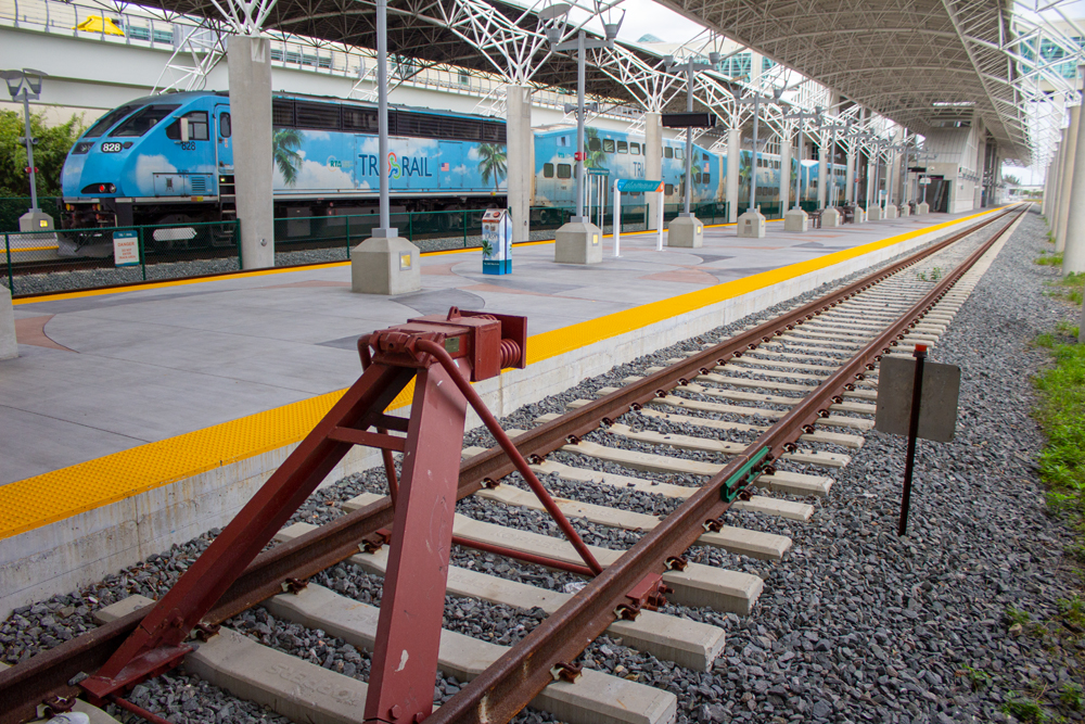 Empty track in foreground at station with commuter train in background.