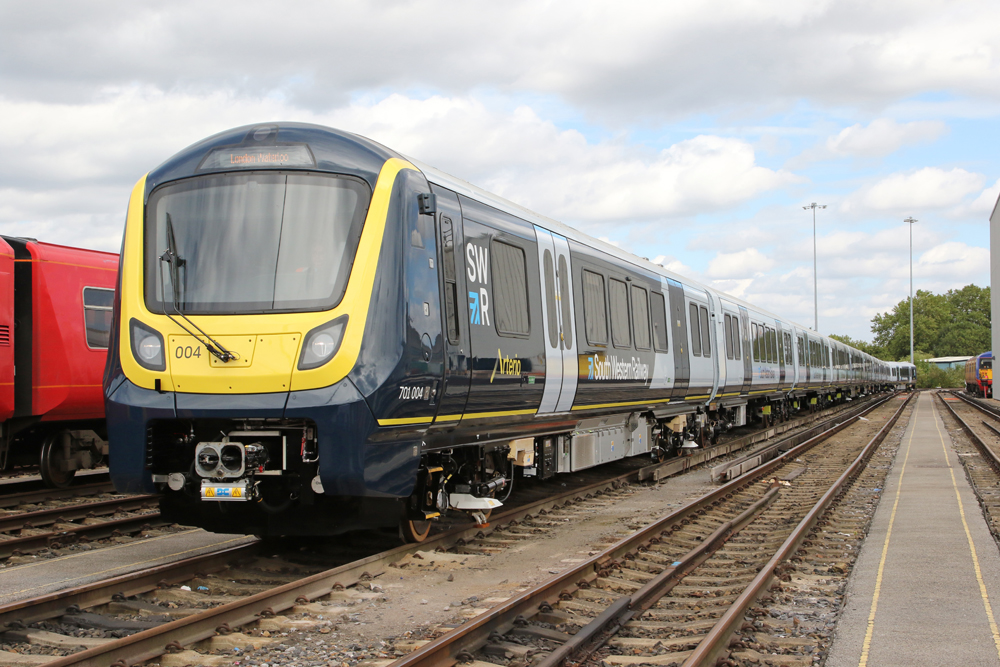 New blue and yellow passenger train sits in yard