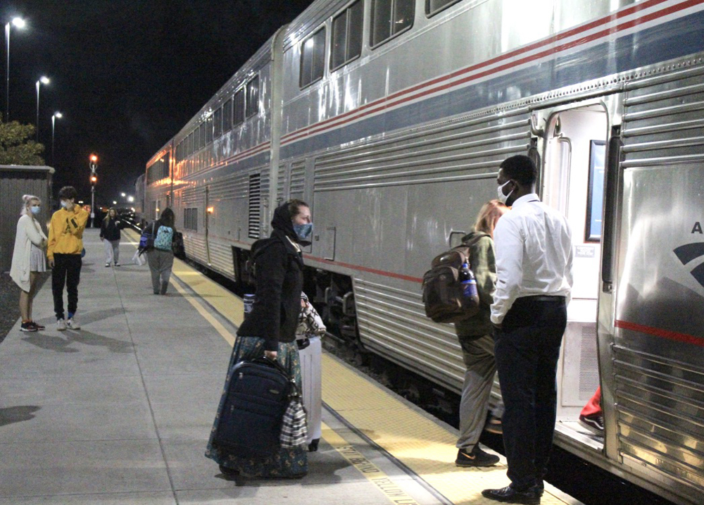 People boarding bilevel Amtrak passenger car at night