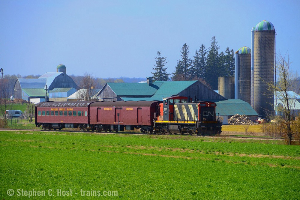 Black-and-white striped locomotive pulling two vintage passenger cars