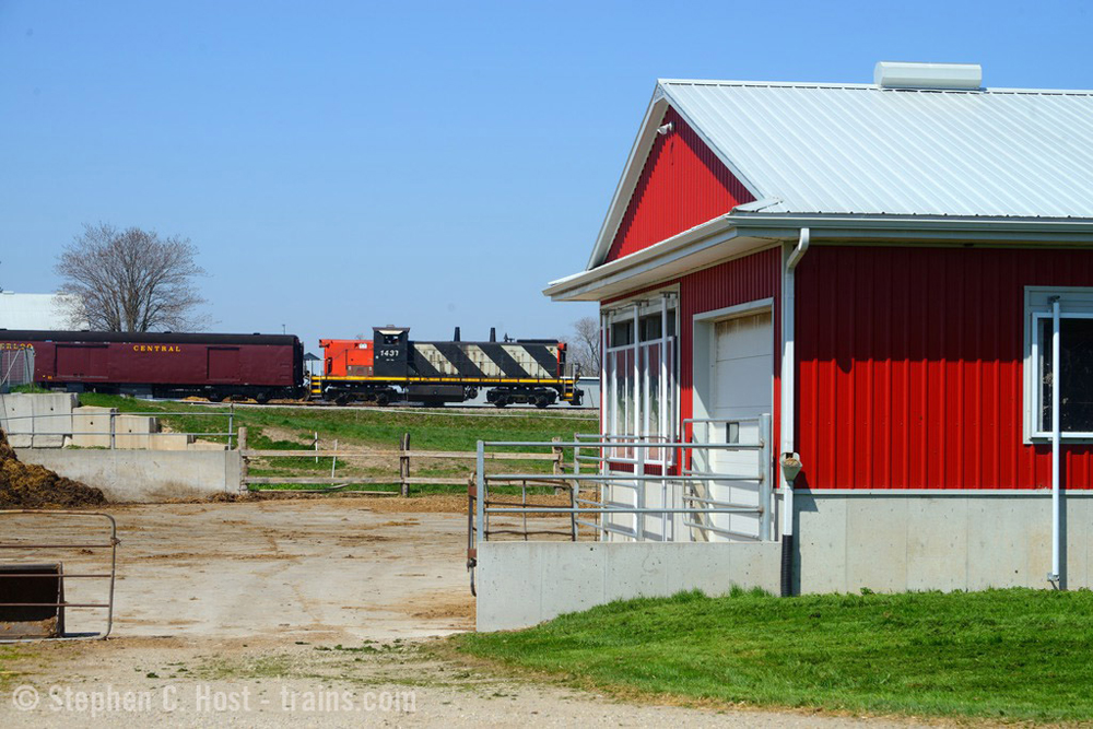 With red building in foreground, train passes in distance