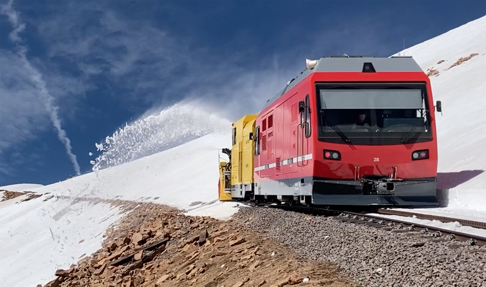 Yellow snow blower and red boxcab locomotive