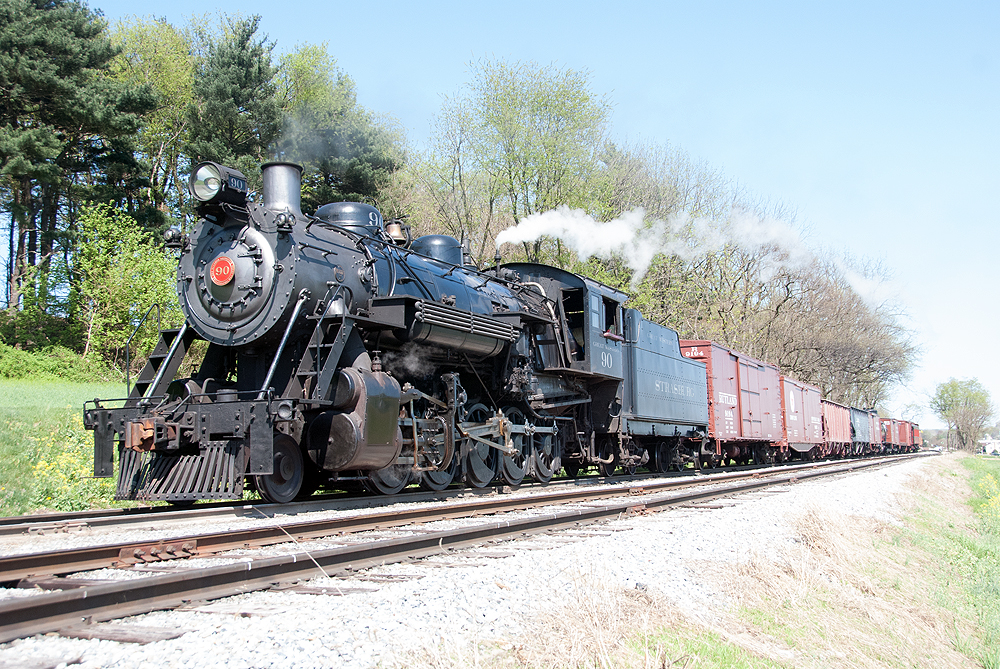 Steam locomotive hauling a freight train on a sunny day.