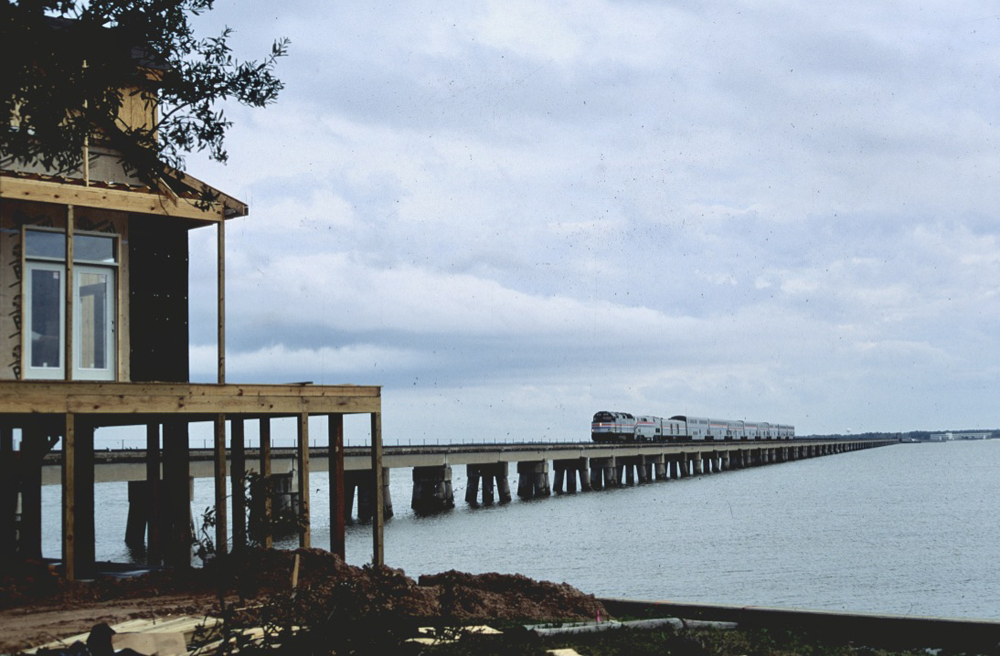 Passenger train crossing long bridge at dusk