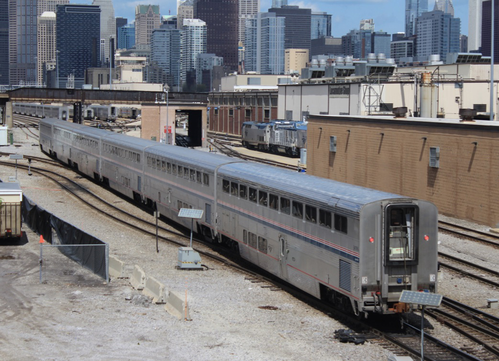 Back end of passenger train arriving in Chicago, with skyline in distance