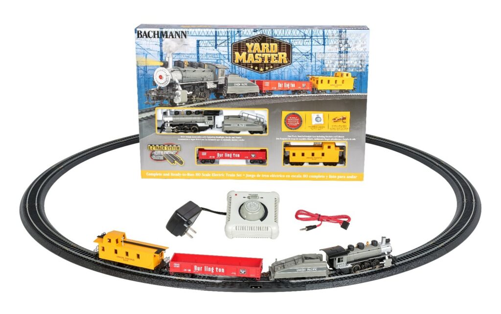 an HO scale toy train set featuring a box containing a steam locomotive, train cars, and track