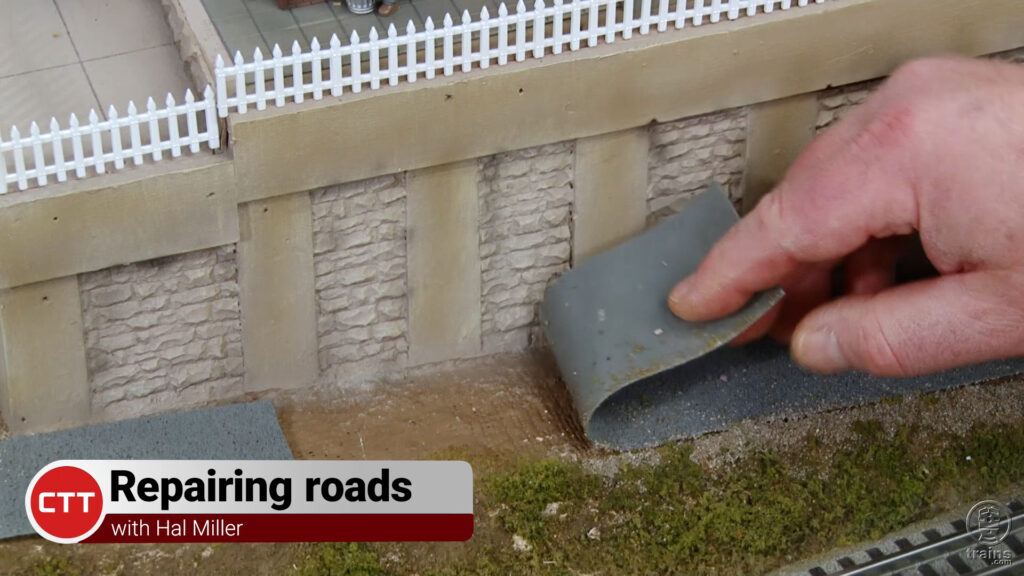 Hand gluing a model road on a layout