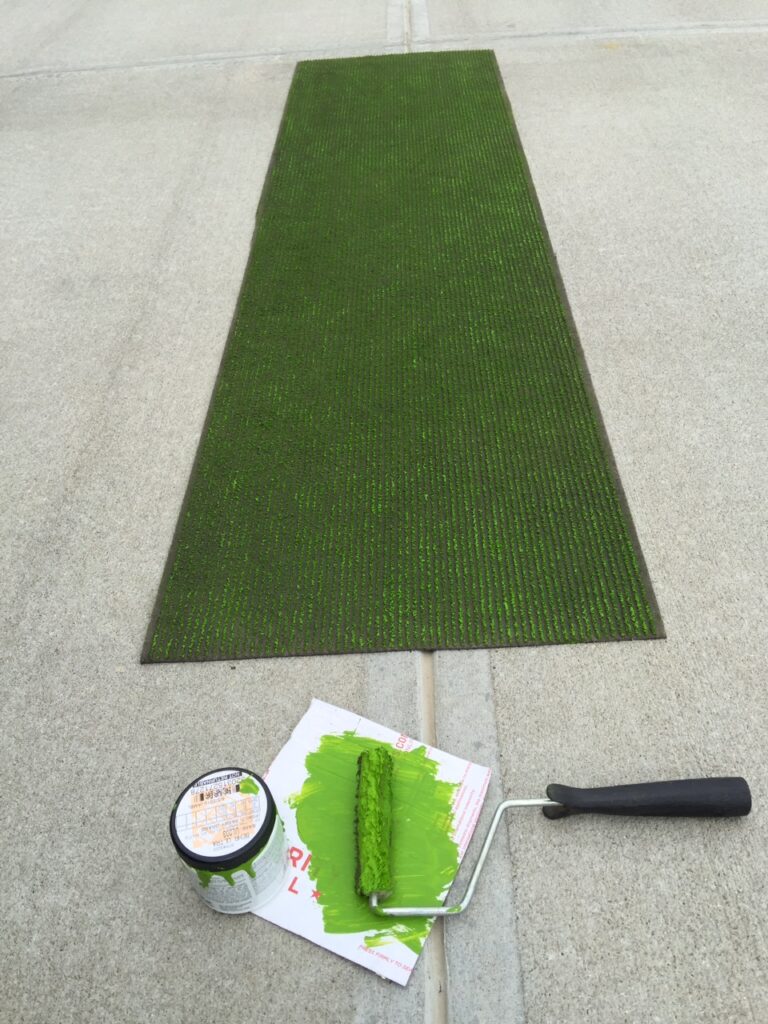 Painting a piece of carpet runner with green paint