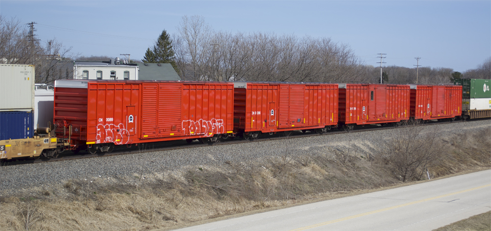 Four red CN high-cube distributed braking cars in the middle of an intermodal train.