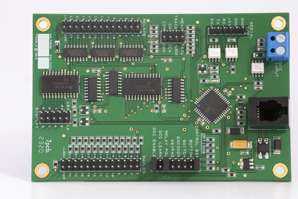 Green rectangular circuit board with blue screw terminals in upper right, white plug terminals in upper left