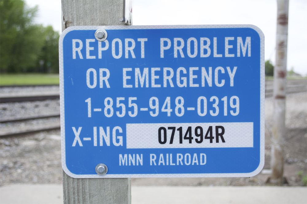 Minnesota Northern RR Emergency Notification System sign attached to wood post.