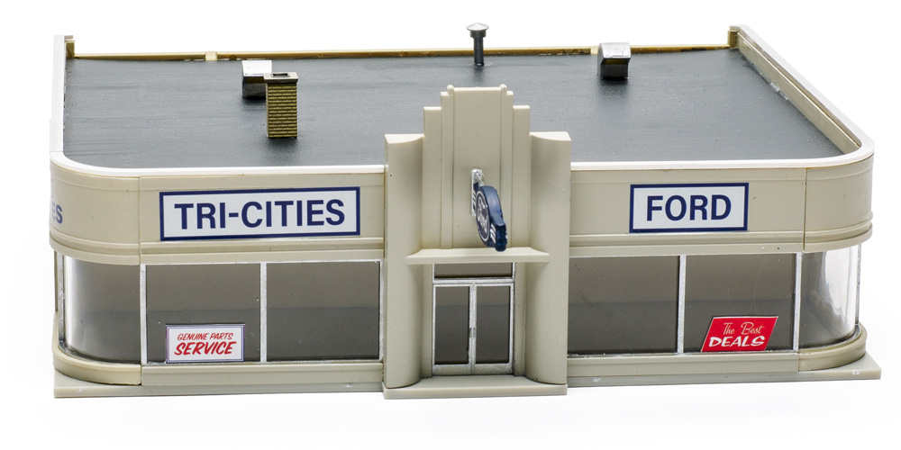 An assembled HO scale kit of an Art Deco-style city auto dealership with large, curved front windows