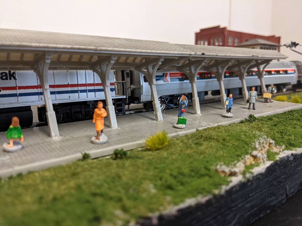 Model figures idling on a station platform with an Amtrak train pulled up