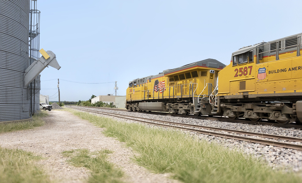 A pair of yellow Union Pacific diesels are seen in low angle in a rural scene