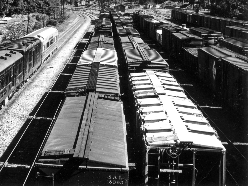 The roofs of several freight cars are seen in a black-and-white photo of a rail yard