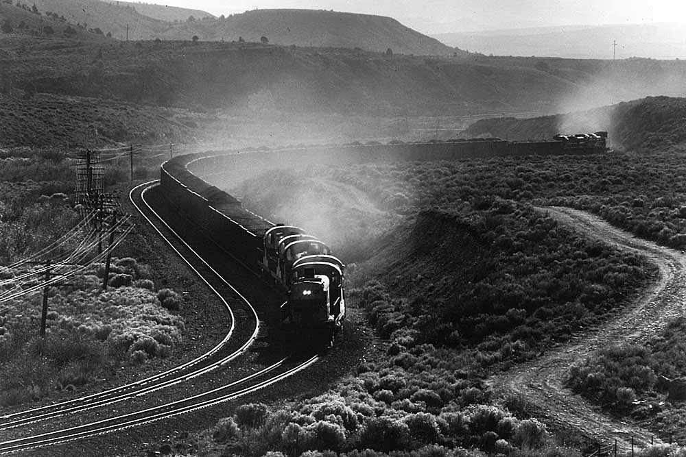 Sun highlight diesel locomotive exhaust of train in curve