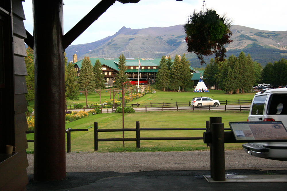 Large wooden lodge building, seen across large expanse of grass from station