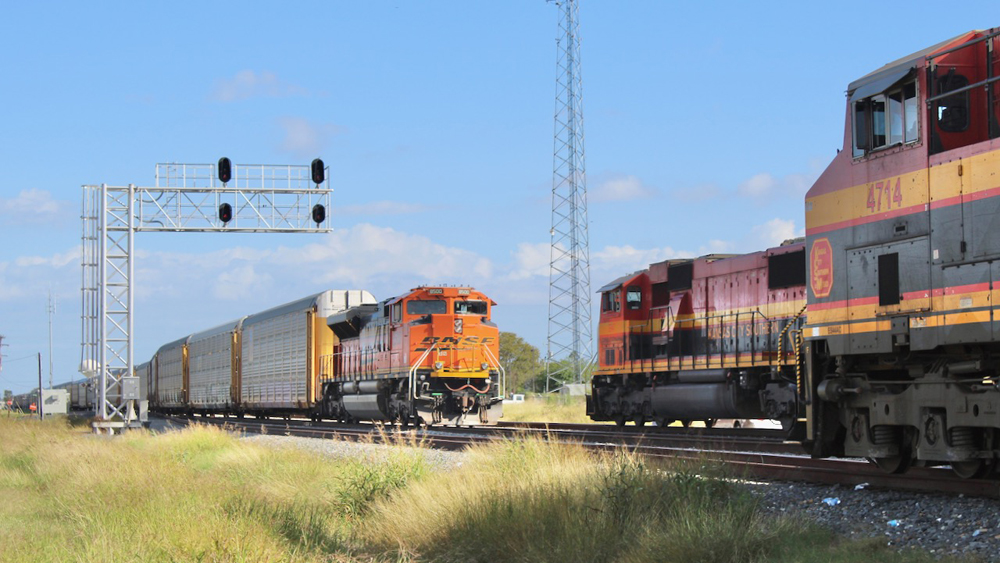 Train with BNSF locomotive passes Kansas City Southern engines