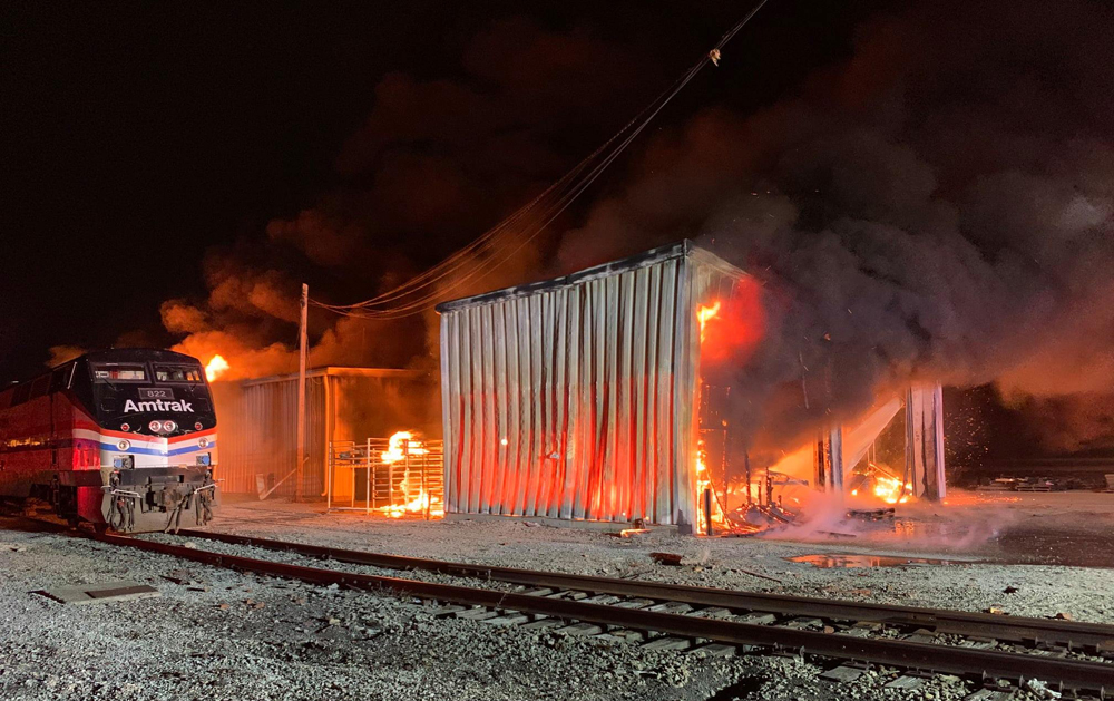 Buildings on fire next to Amtrak locomotive