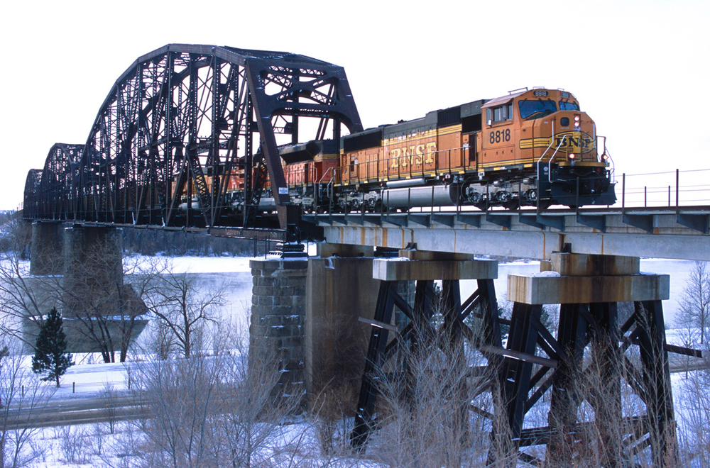 BNSF train crossing river bridge in winter