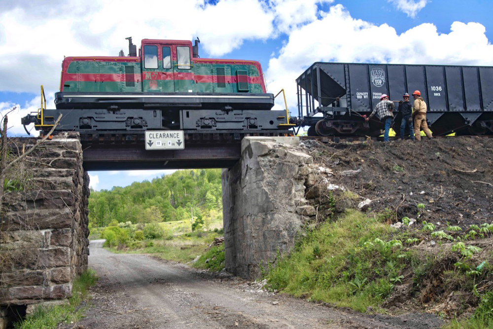 Diesel lcomotive with ballast cars on small bridge