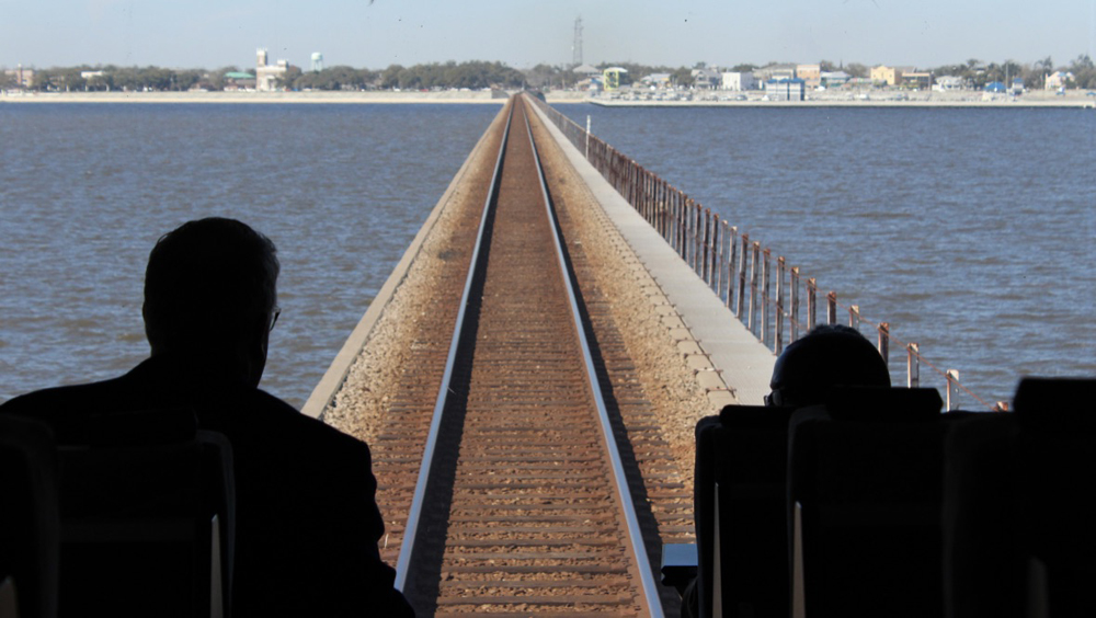 Two people looking at railroad track on bridge