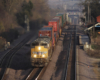 Container train with yellow locomotives approaches on the middle of three tracks.