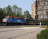 Commuter train with blue locomotive passes in background with post office sign in foreground.