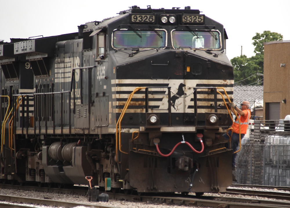 Man in orange vest climbing onto black locomotive