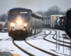 Passenger train passes through S curve on one track as freight train passes in other direction.