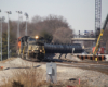 Black diesels lead long string of tank cars through curves. 