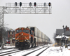 Container train rolls under signal bridge as it passes commuter station