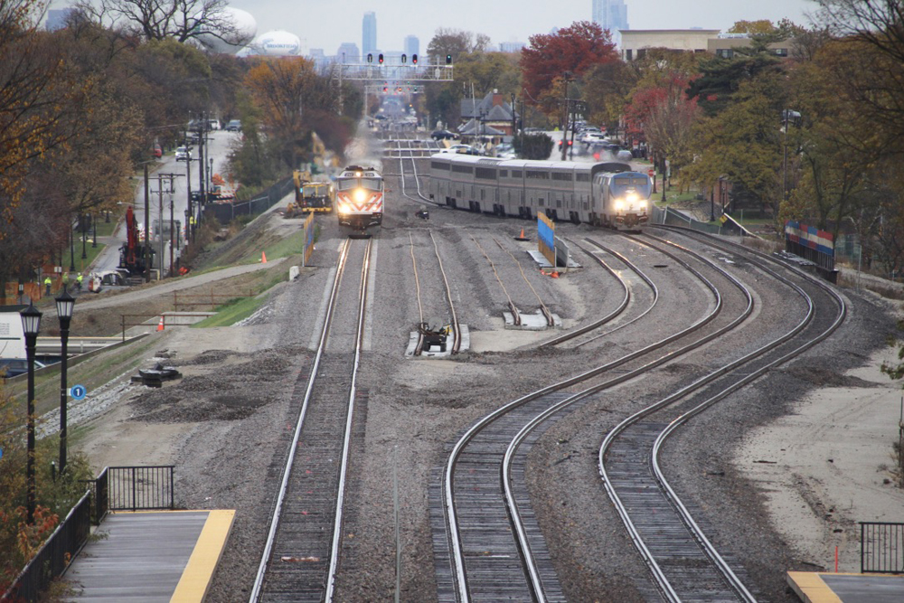 Side-by-side trains, one taking a straight track and another going around a curve