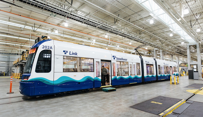 White and two-tone blue light rail car in shop
