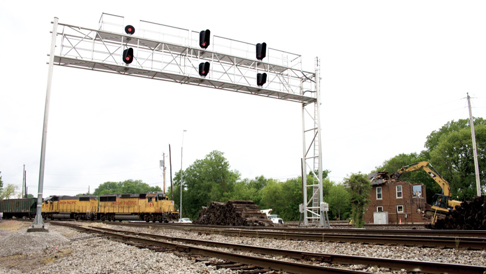 Freight train crosses tracks near building being demolished