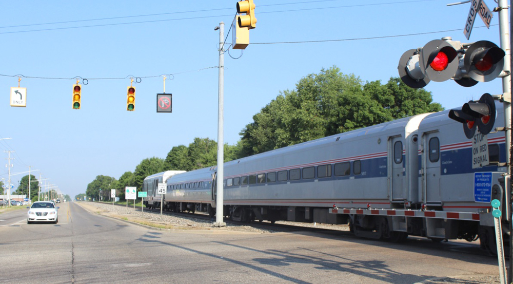 Passenger train paralleling highway passes grade crossingWolverine No. 351 heads toward Kalamazoo and Chicago on July 7, 2020, west of Galesburg, Mich., on another 110 mph. portion of the Chicago-Detroit route