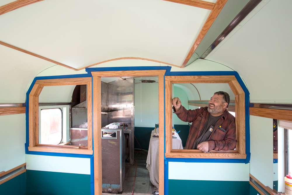 Man inside passenger car inspecting woodwork