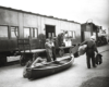 Two men stand on a train platform with a canoe