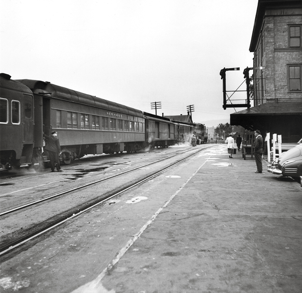 A trains sits as a conductor stands by the open door