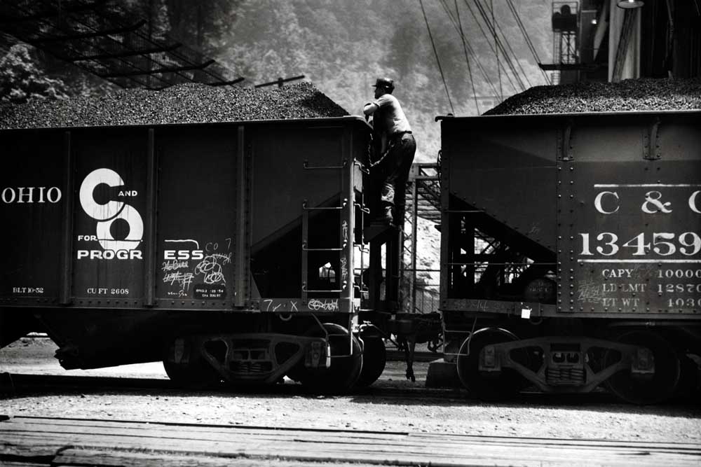 Man climbing between two coal hopper cars