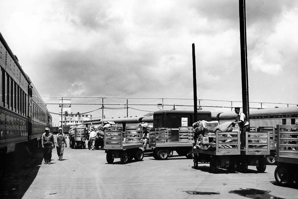 Carts and workers handling mail outdoors at large passenger terminal