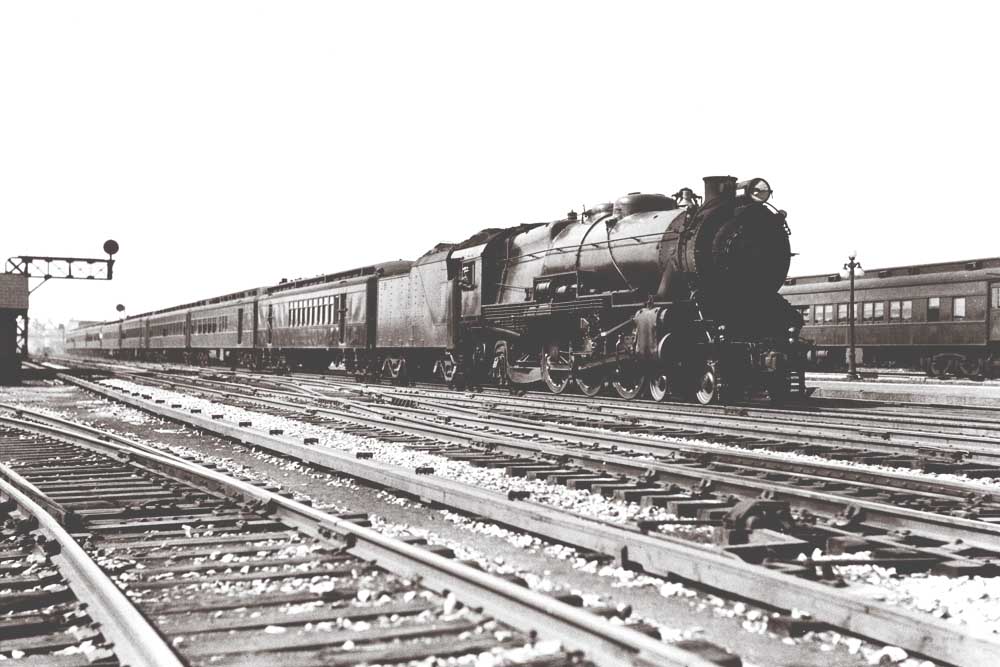 Steam locomotive with passenger train by signal gantry