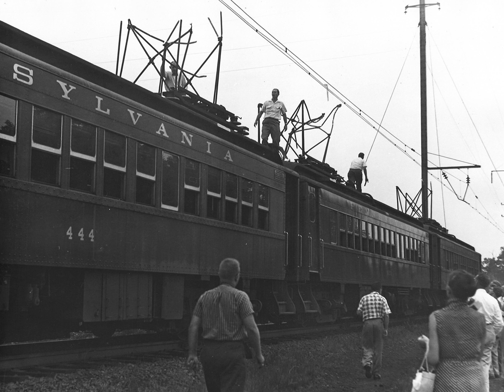 People on right of way beside electric multiple-unit train