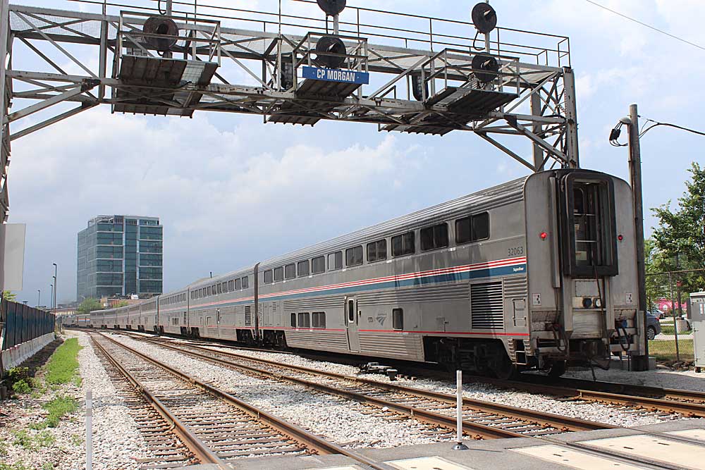 Passenger train passing under overhead signal bridge on multi-track route